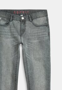 Jeans de mezclilla gris con un acabado desgastado, diseño de cinco bolsillos, cierre de botón y logo de Esprit en la cinturilla. Presenta sutiles desgastes.