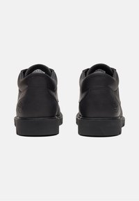 Schwarze Lederschuhe mit glatter Textur, runder Zehenpartie und gepolstertem Kragen; verfügt über ein geprägtes Logo an der Ferse und eine robuste schwarze Gummisohle.