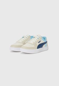 Sneaker basse beige e blu con tomaia perforata, suola in gomma, chiusura con lacci e una striscia blu prominente sul lato.