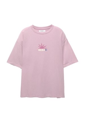 Lichtroze oversized t-shirt van katoen met een grafisch ontwerp van een zon en de tekst "IBIZA 91" in contrasterende kleuren op de voorkant gedrukt.