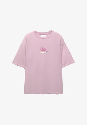 Lichtroze oversized t-shirt van katoen met een grafisch ontwerp van een zon en de tekst "IBIZA 91" in contrasterende kleuren op de voorkant gedrukt.