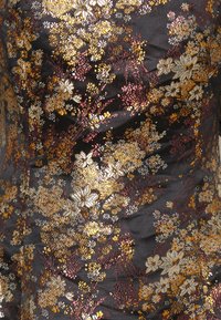 Tissu noir orné d'une broderie florale complexe en or, argent et bordeaux, présentant des formes et textures florales variées.