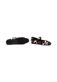 Ballerines noires et brown à motif vache avec un nez rond, une sangle Mary Jane et une semelle en caoutchouc texturée pour l'adhérence. Matière en tissu doux.