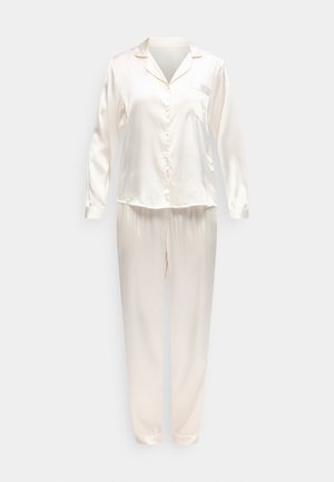 Ensemble de pyjama en satin couleur crème composé d'une chemise à manches longues boutonnée et d'un pantalon assorti sur un fond uni.