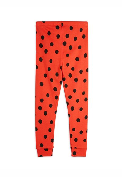 Red leggings made from soft fabric, featuring a pattern of large black dots, with elastic cuffs at the ankles and a fitted design.