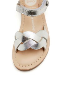 Sandalo in pelle argento con design a nastro intrecciato, punta aperta, cinturino alla caviglia regolabile e soletta imbottita beige.