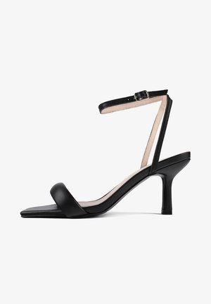 Sorte læder hælede sandal med firkantet tå, tynd ankelrem og en mellem-høj stilettohæl. Glat tekstur med minimal hardware.
