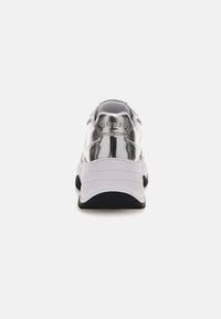Witte en metallic zilveren sneaker met een ronde neus, gevoerde kraag en zwarte buitenzool. Bevat het "GUESS" logo op de hiel en zijkant.