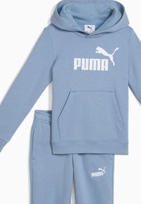 Sweatshirt azul claro e calças de treino combinando, feitas de um tecido macio. Apresenta um bolso frontal e o logótipo branco da Puma em ambas as peças.