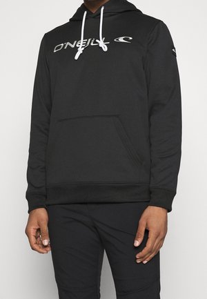 Person trägt einen schwarzen O'Neill Hoodie mit weißen Kordeln und schwarze Hose, steht vor einem einfarbigen hellen Hintergrund.