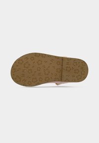 Semelle d'une sandale marron clair avec des motifs de fleurs et de feuilles sur un fond blanc.