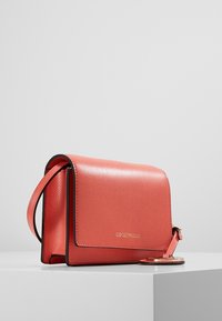 Borsa a tracolla in pelle corallo con design strutturato, dotata di chiusura a patta, dettagli neri e un portachiavi staccabile con logo.