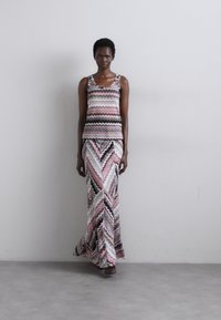 Completo in due pezzi composto da un top senza maniche e una lunga gonna a fantasia. Il design include strisce a zigzag in tonalità di rosa, bianco e nero.
