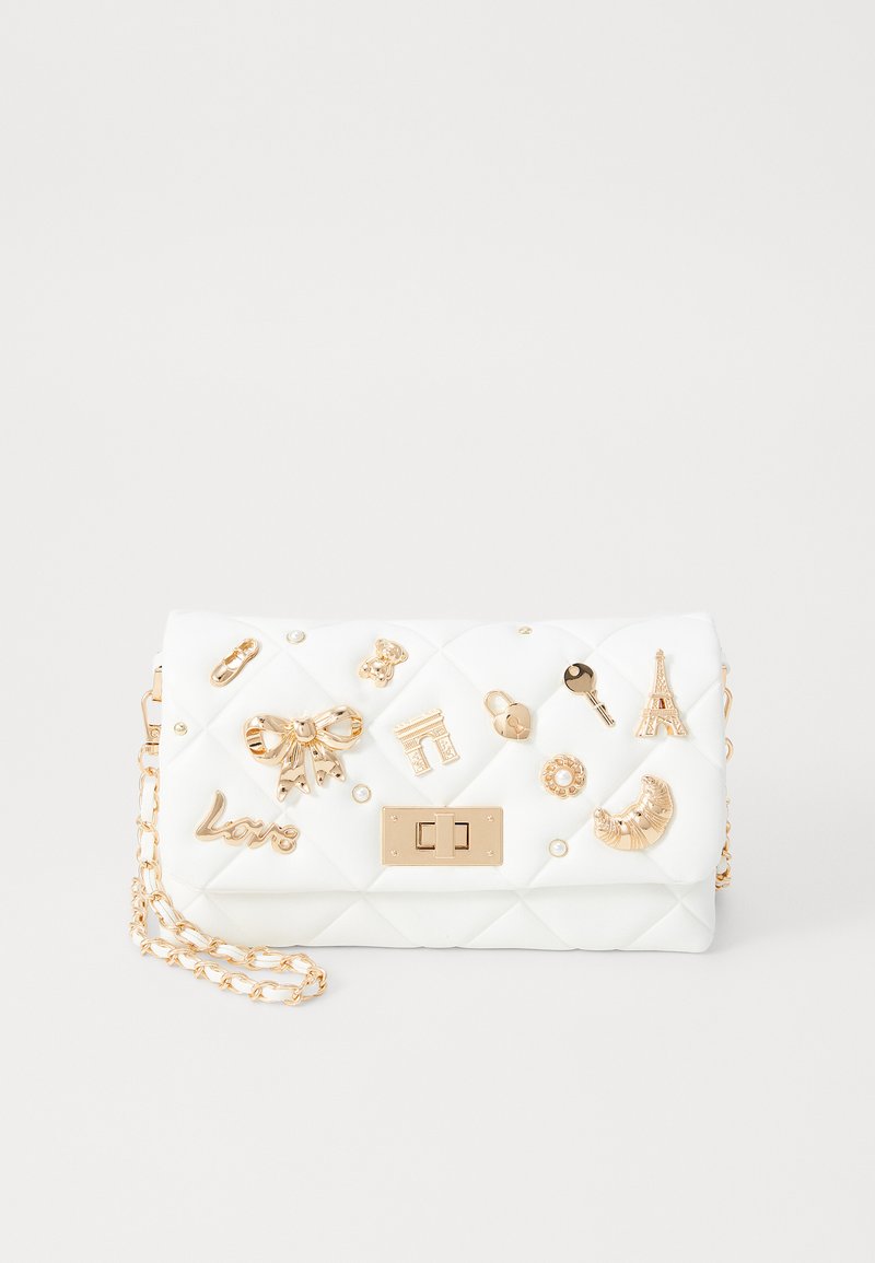Borsa a tracolla bianca trapuntata con charms decorativi in tono oro, una tracolla a catena e una chiusura frontale. Texture liscia con dettagli impreziositi.