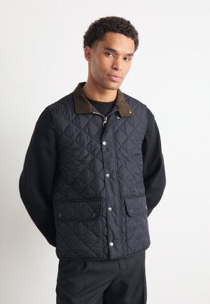 Quilted navy vest with brown corduroy collar, two front pockets, and snap buttons. Designed with a lightweight, textured fabric.