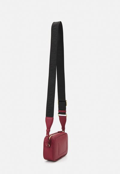 Borsa a tracolla rossa in pelle con superficie testurizzata, forma rettangolare e una tracolla nera regolabile con dettagli di branding impresso.