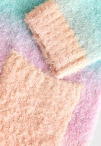 Deux morceaux de tissu texturé aux teintes pastel de pêche et de menthe, mettant en valeur des fibres bouclées et duveteuses sur un fond dégradé doux.