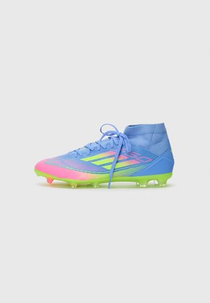 Chaussure de football bleue et rose avec une tige semblable à une chaussette, détaillée avec des motifs colorés et une semelle verte. Comprend un système de lacets et des crampons.