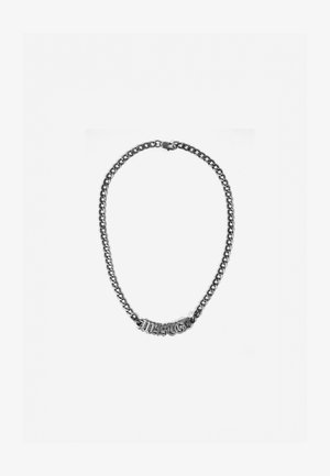 Srebrny metalowy naszyjnik z łańcuchem o grubych ogniwach i dużą ozdobną sekcją z stylizowanym napisem na środku, wypolerowane wykończenie.