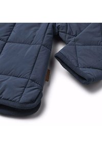 Quiltad marinblå jacka med ett mjukt innerfoder, med en rundad krage, mönstrade ärmslut och en liten tygetikett.