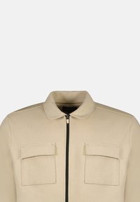 Beige jas met een kraag, ritssluiting aan de voorkant en twee borstzakken. Gemaakt van zacht materiaal met een minimalistisch ontwerp en strakke lijnen.