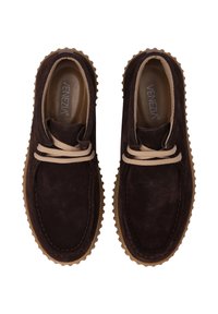 Dunkelbraune Wildlederschuhe mit runder Form, cremefarbenen Schnürsenkeln und einer strukturierten Gummi-Sohle, die ein genähtes Randdetail aufweist.