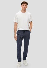 Weißes Baumwoll-T-Shirt kombiniert mit navy-blauen gestreiften Hosen aus leichtem Material, mit elastischem Bund und Seitentaschen.