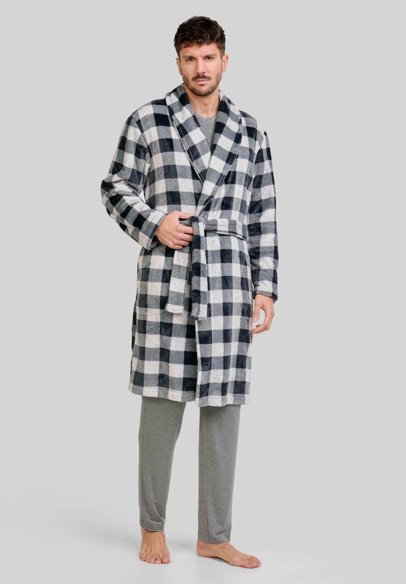 Bata de franela en patrón de cuadros en blanco y negro, con cuello chal, cinturón de lazo y mangas largas, usada sobre pantalones grises.