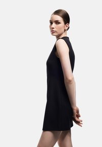 Vestido negro sin mangas con una silueta ajustada, textura suave y diseño minimalista. Presenta un escote redondo y una longitud por encima de la rodilla.
