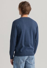 Marineblauer gestrickter Pullover mit langen Ärmeln, gerippten Bündchen und Saum, Rundhalsausschnitt und glatter Textur. Rückansicht gezeigt.