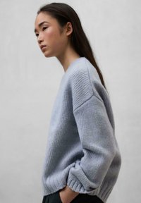 Light blue, knitted sweater with ribbed cuffs and a round neckline. Features a relaxed fit and textured yarn. Clean, minimal design.