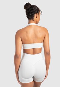 Vit ribbad crop top med halterneck och matchande högmidjade shorts med rundad fåll. Slät struktur, minimalistisk design.