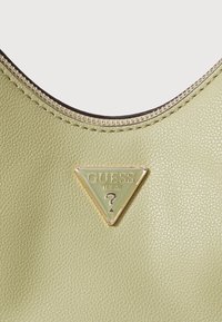Borsa a tracolla in pelle verde testurizzata con logo triangolare dorato. Presenta una chiusura con zip e un bordo nero a contrasto lungo il margine superiore.