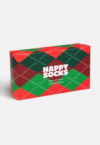Scatola regalo rossa e verde con un motivo a diamante e accenti bianchi, etichettata "HAPPY SOCKS," contenente tre paia di calzini.
