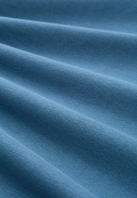 Niebieska tkanina o gładkiej fakturze, wykazująca delikatne fałdy i jednolity, miękki wygląd, odpowiednia do różnych zastosowań.