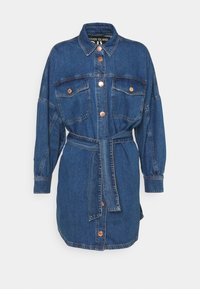 Jeanskjol i mörkblått med långa ärmar, knäppning fram, två bröstfickor och ett matchande bälte i midjan. Kopparfärgade knappar som accent.