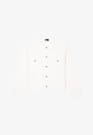 Chemise blanche à boutons avec un col, des manches longues et deux poches poitrine, ornée de boutons noirs. Texture de tissu doux.