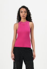 Sopiva, hihaton crop-top kirkkaan vaaleanpunaisena, valmistettu ribatusta kankaasta, jossa on kontrastiväristä hopeanväristä ommelta kaula-aukossa ja käsivarsinauhoissa.