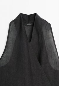 Černý pletený top bez rukávů s hlubokým výstřihem do V a měkkým límcem, značka Massimo Dutti, vyrobený v Maroku.