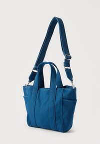 Μικρή μπλε υφασμάτινη τσάντα tote με κοντές χειρολαβές και μακρύ ρυθμιζόμενο ιμάντα ώμου με το λογότυπο Calvin Klein.