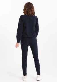 Marineblauw bijpassend setje met een longsleeve top met pofmouwen en slim-fit broeken. Gemaakt van een zachte, rekbare stof.