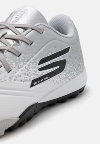 Gray sports shoe with a textured upper, featuring a gradient pattern, black accents, and a rubber sole designed for traction.