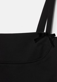 Borsa a tracolla nera in tessuto liscio, con dettaglio a fiocco e spallacci larghi. Design semplice con parte superiore curva e cuciture discrete.