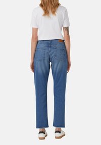 Modré denimové džínsy s rovnými nohavicami, ktoré majú dve zadné vrecká, koženú nášivku na páse a surové zakončenie.