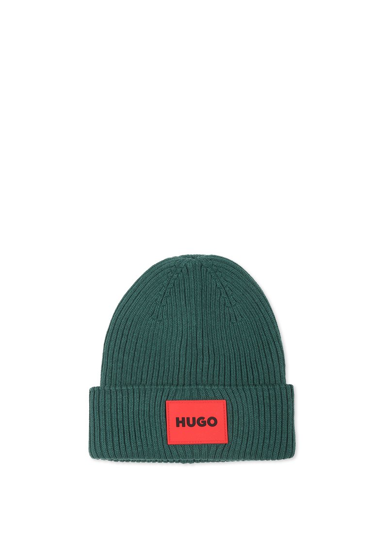 Bonnet en tricot vert avec une texture côtelée, présentant une patch rectangulaire rouge avec du texte noir. Design classique à revers.