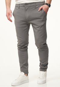 Gray cotton blend pants with a slim fit, featuring front pockets and a button closure, paired with white sneakers.