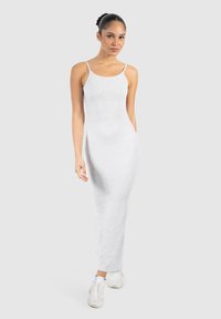 Robe maxi sans manches blanche en tissu côtelé, avec un design ajusté qui va jusqu'aux chevilles. Apparence plate et minimaliste.