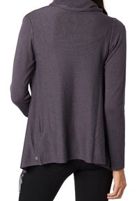 Mörklila långärmad topp med cowl-hals, texturerat tyg och avslappnad passform. Har en krökt nederkant och en liten logotyp på sidan.