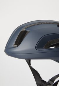 Granatowy kask rowerowy z gładką powłoką, teksturowanymi otworami wentylacyjnymi i czarnymi regulowanymi paskami. Charakteryzuje się smukłym designem.