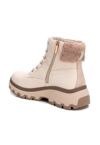 Botas de tobillo beige con cuello de piel sintética, suela acolchada, cremallera lateral y ojales metálicos. Material duradero con detalles texturizados.